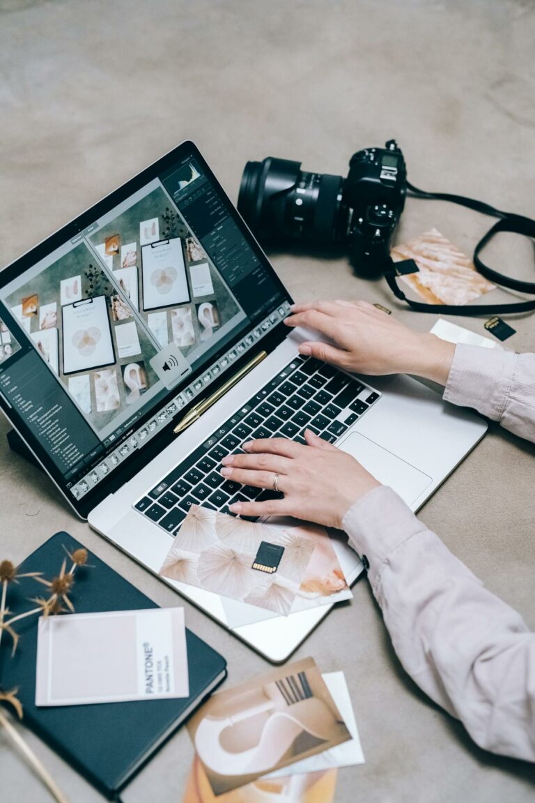Hands editing photos on a laptop with a camera nearby, showcasing modern technology and creativity.